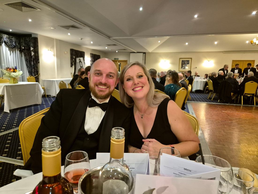 A member and his partner at a black tie dinner