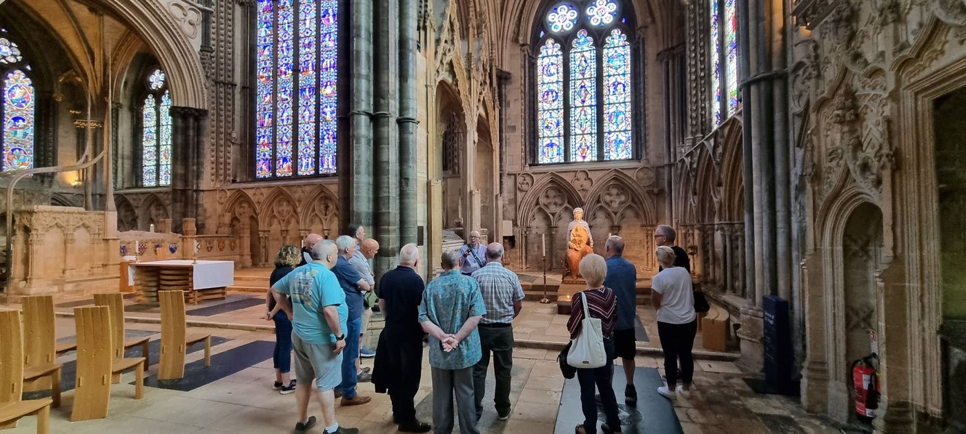 Members on a guided tour beneath stained glass windows in Lincoln Cathedral