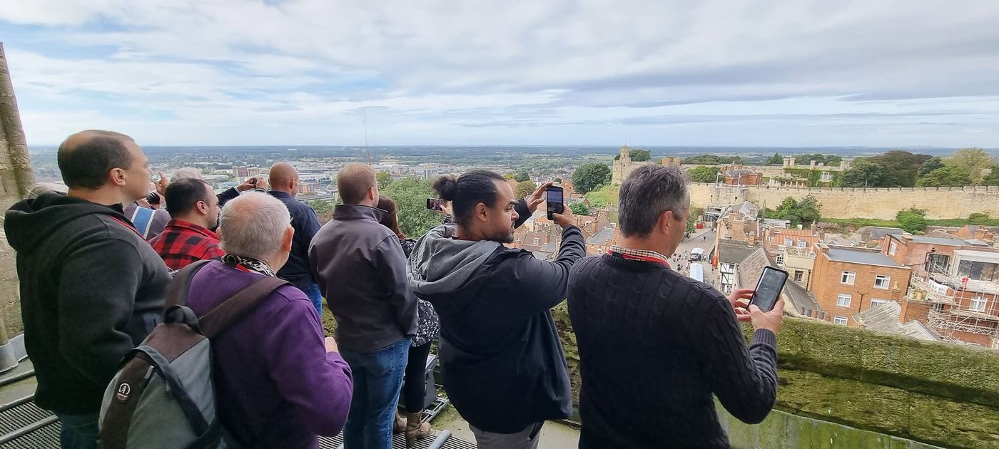 Members taking photos from high up on Lincoln Cathedral, looking over the castle