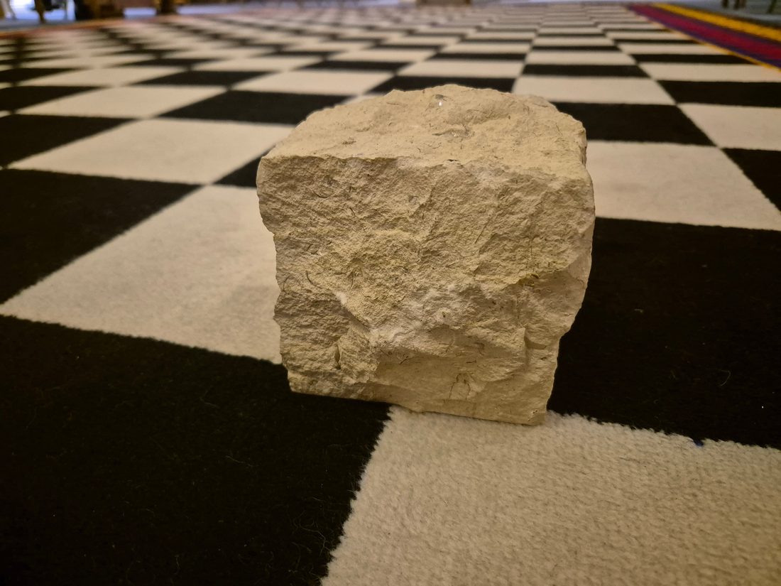 A rough ashlar resting on the lodge's black and white chequered floor
